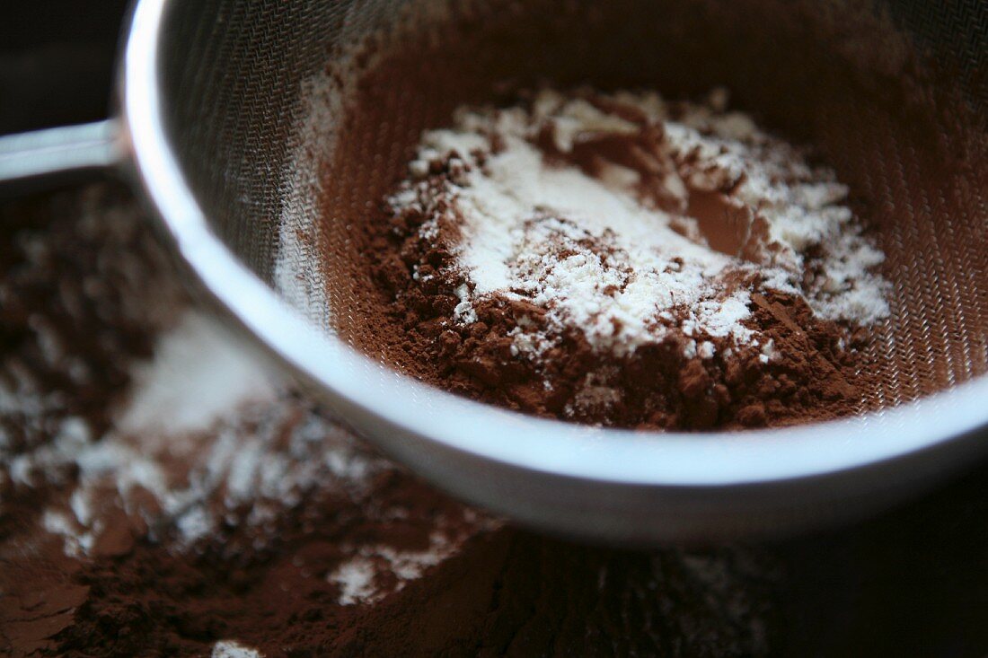 Flour and cocoa being sieved for chocolate cake