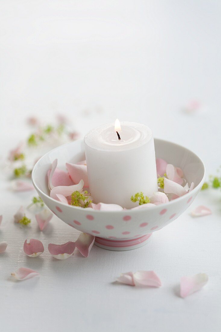 Candle in a little bowl surrounded by petals