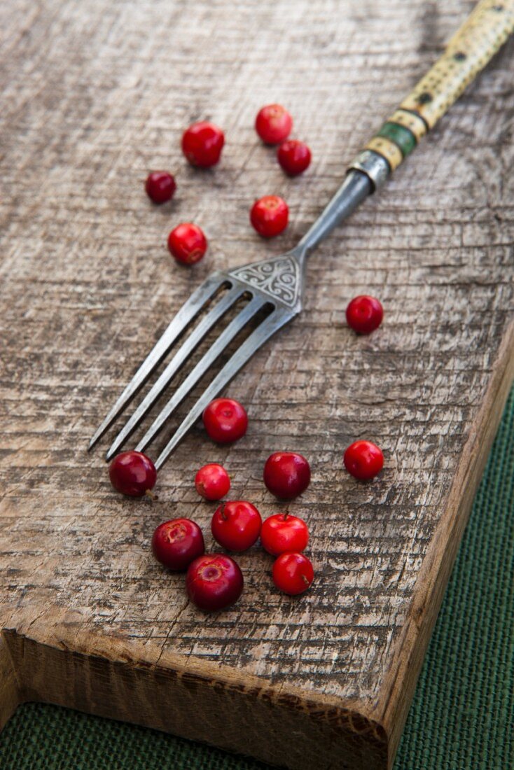 Lingonberries with a fork on a wooden board