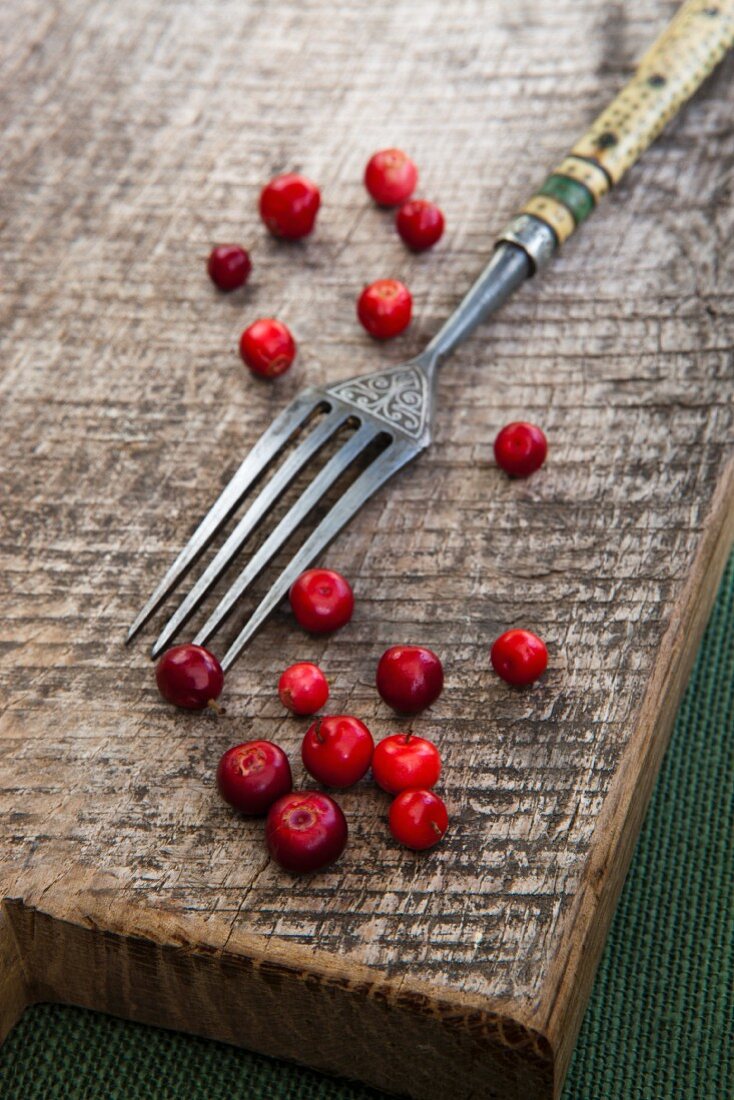 Preiselbeeren mit Gabel auf Holzbrett