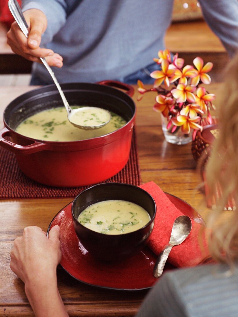 Mann serviert Blumenkohlsuppe