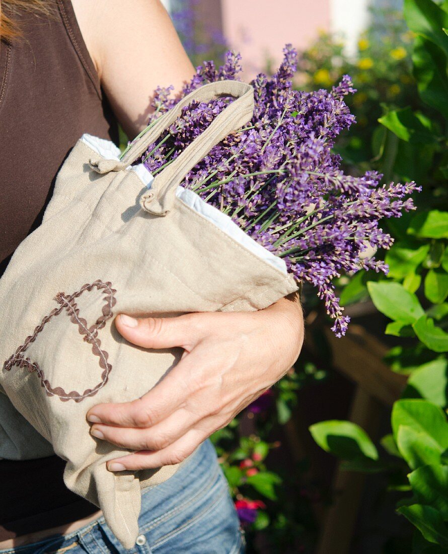 Frau hält Leinentasche mit Lavendelblüten