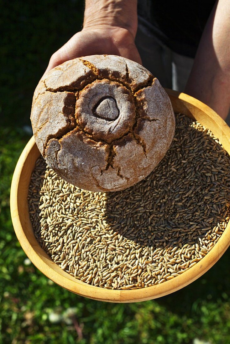 A man holding a bowl of organic rye and a loaf of rye bread