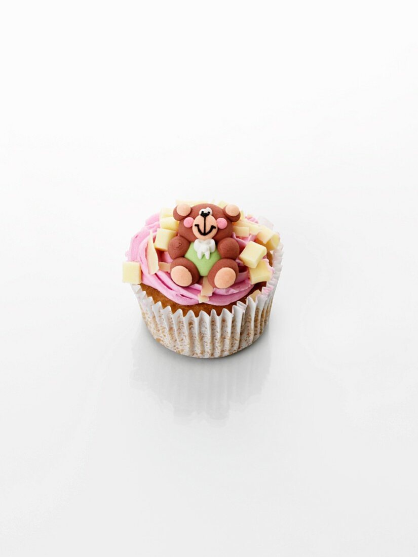 A cupcake decorated with strawberry cream and a teddy bear