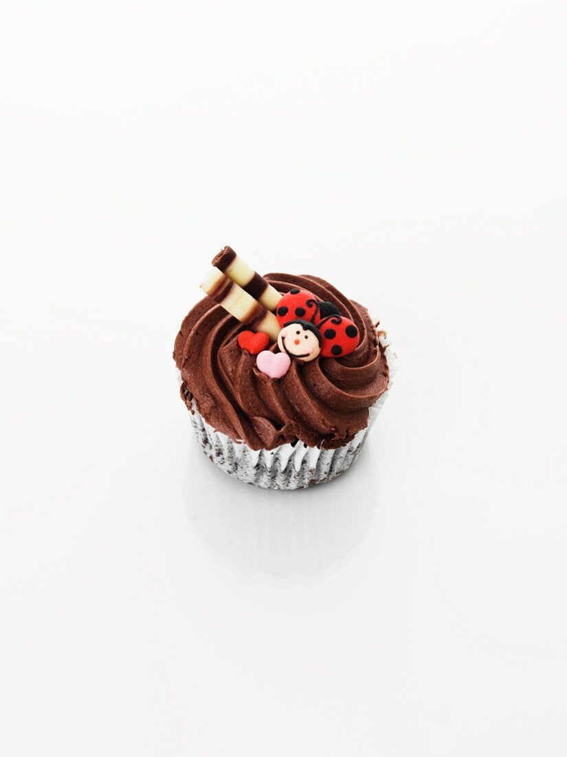 A cupcake decorated with chocolate cream, ladybirds and hearts