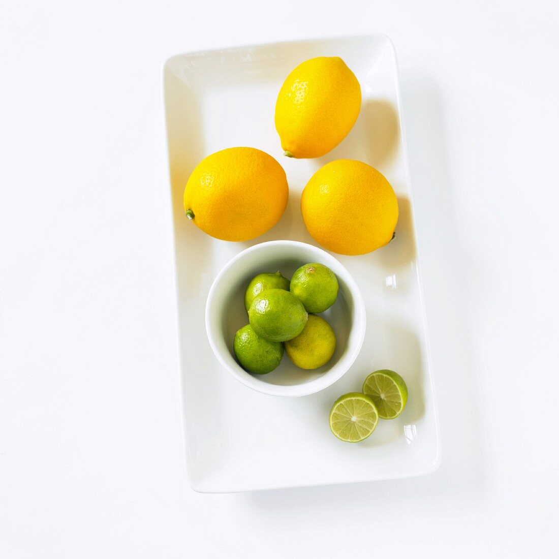 Meyer Lemons & Limetten auf Servierplatte (Aufsicht)