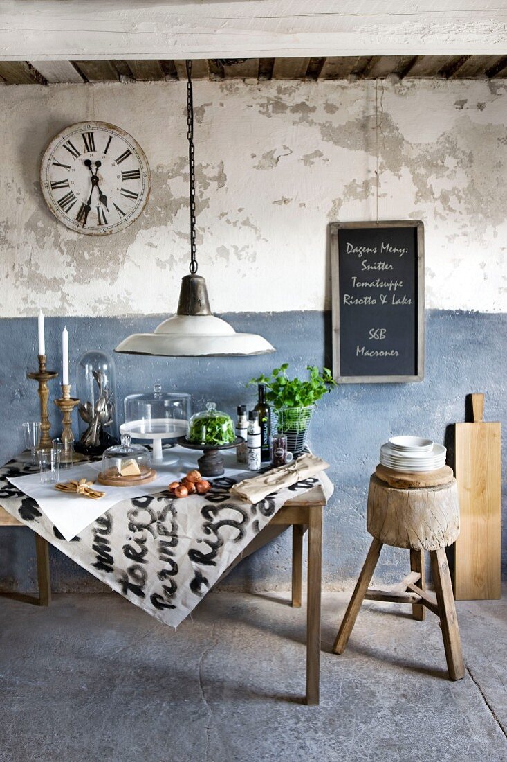 Food and kitchen utensils under glass covers on vintage table against rustic, blue and white wall