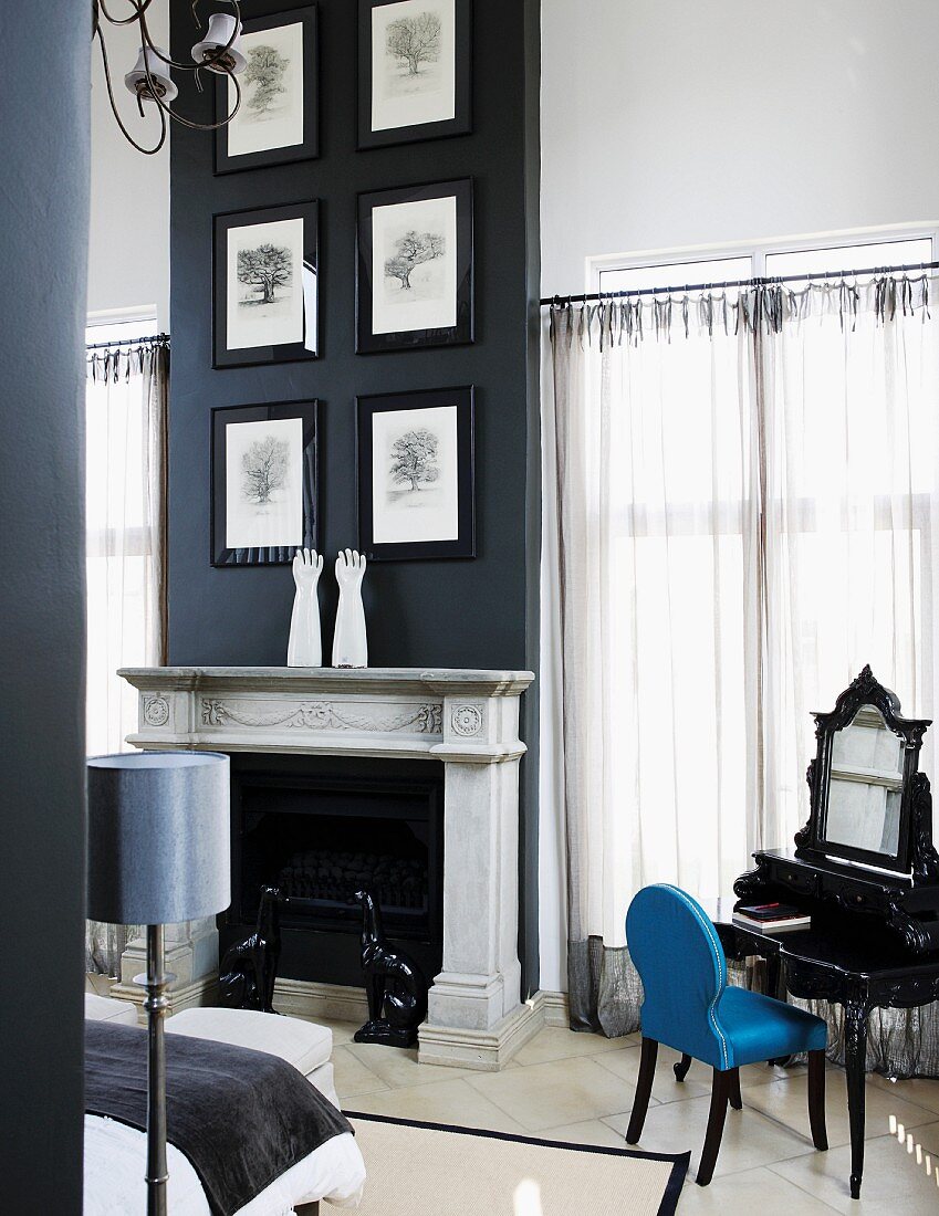 Drawings of trees in black frames hung on black chimney breast above pale marble mantelpiece in grand bedroom