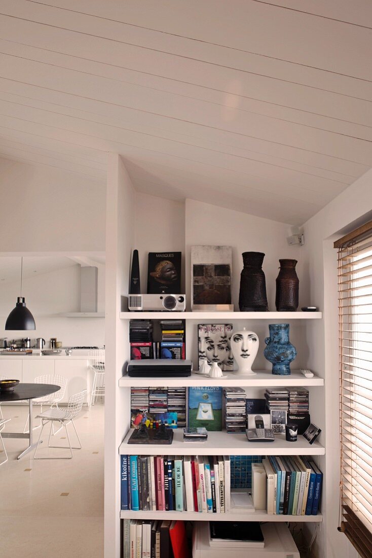 Built in book shelves with books and a view off to the side into an open dining area