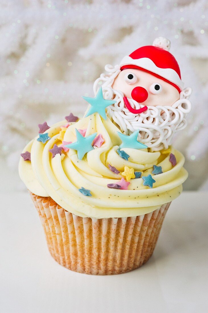 A vanilla cupcake decorated with a Father Christmas and sugar stars