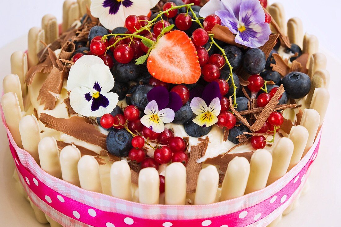 Weisser Schokokuchen mit frischen Beeren und Stiefmütterchen