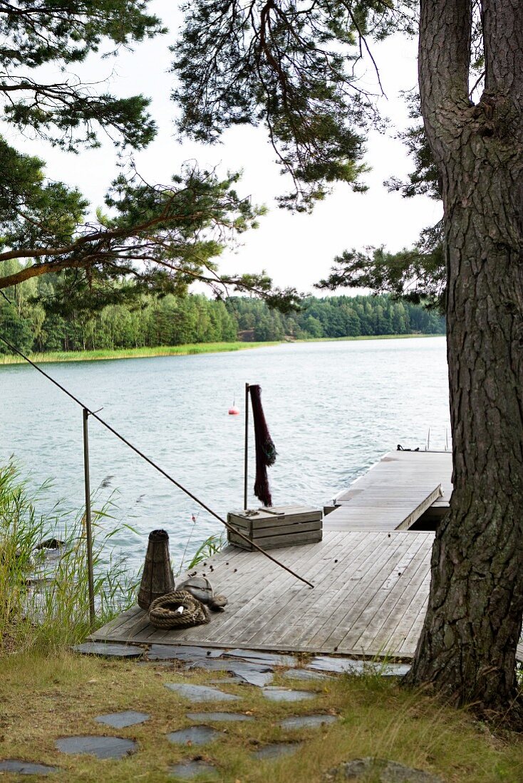 Path paved with stone slabs leading to simple wooden jetty on idyllic lake