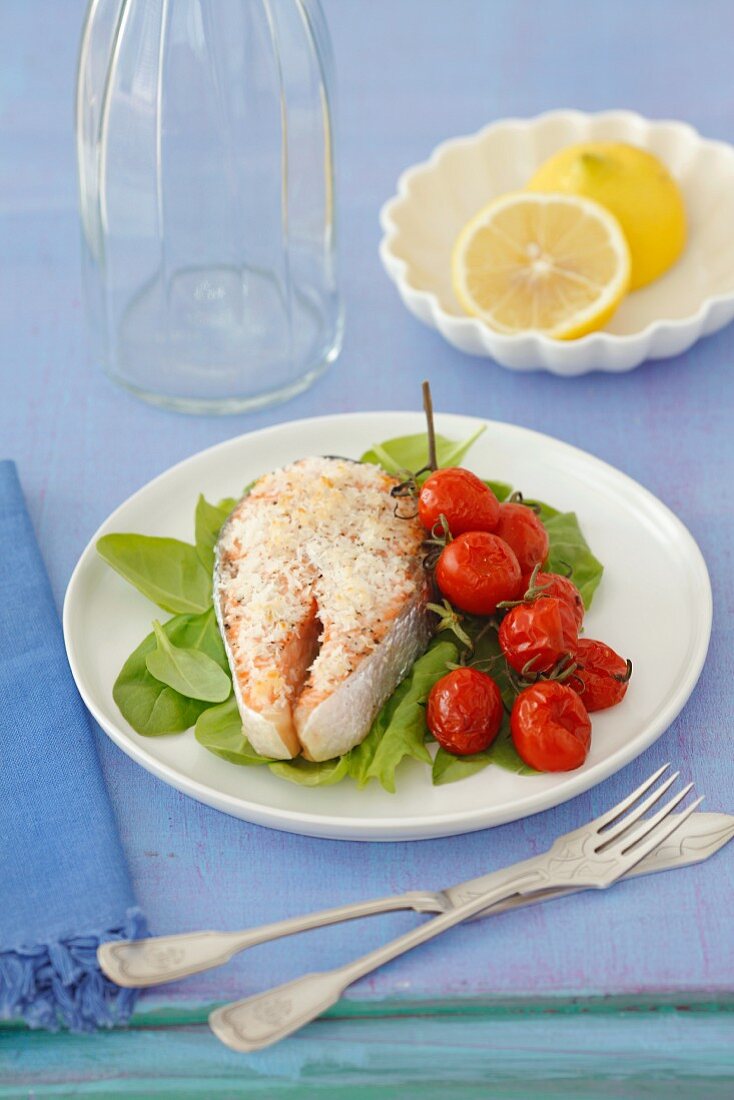 A salmon steak with coconut on a bed of spinach with roasted tomatoes