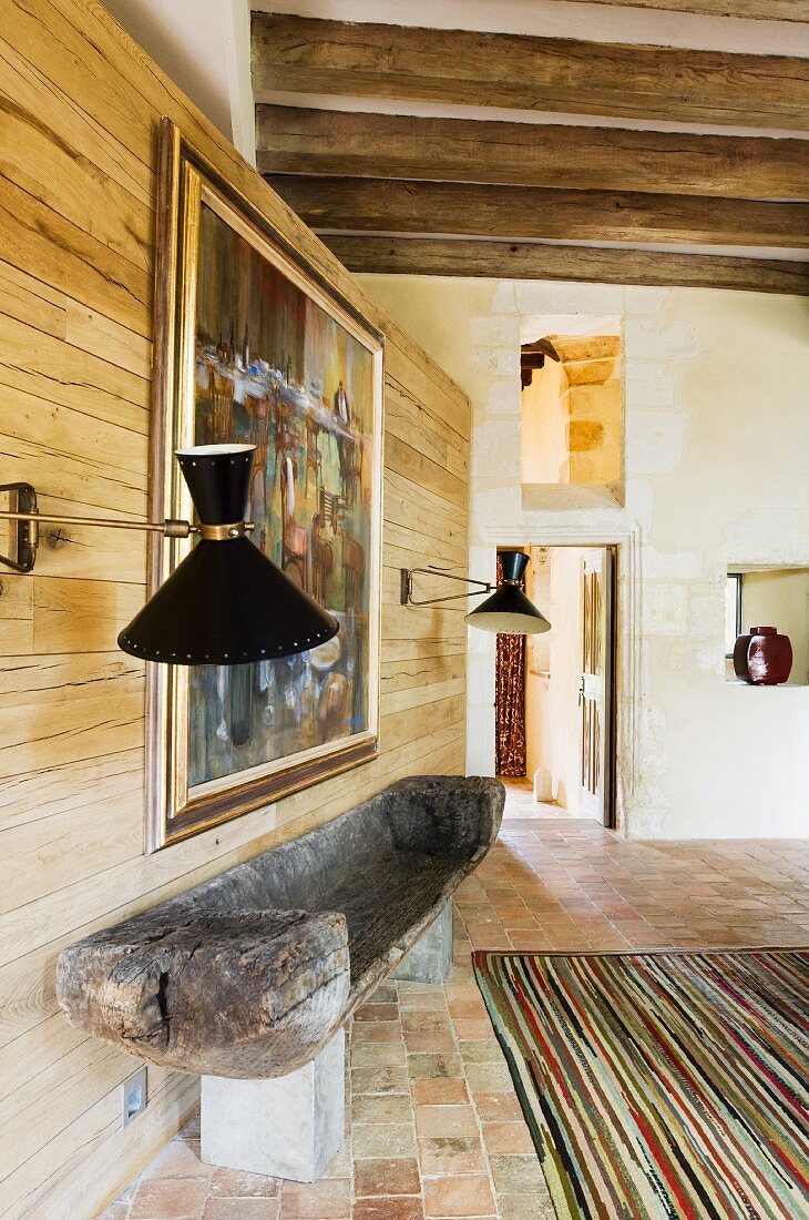 Hand-crafted bench against wooden wall with retro sconce lamps in interior of country house