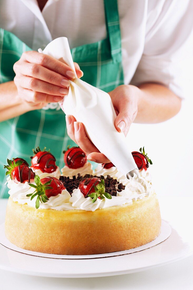 Cream being piped onto a strawberry cheesecake