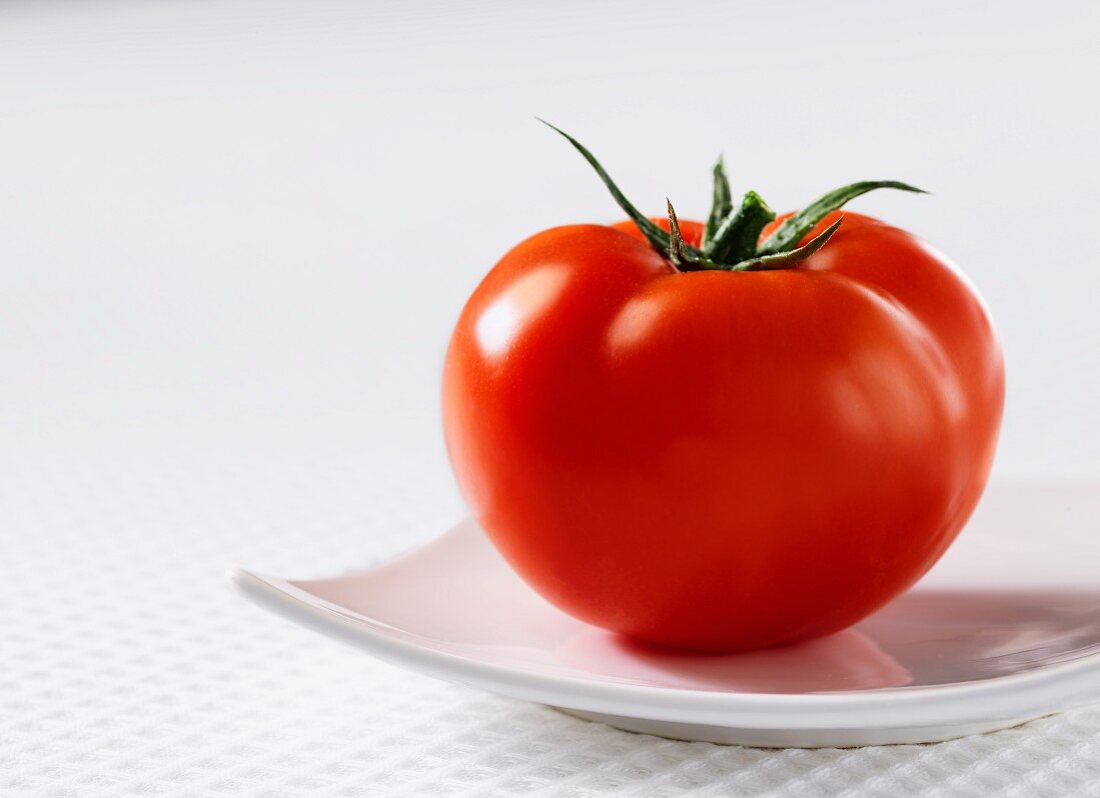 Eine Tomate auf weißem Teller