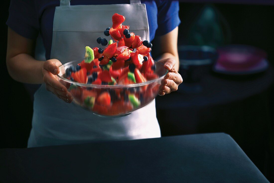 A woman holding a bowl of strawberry salad