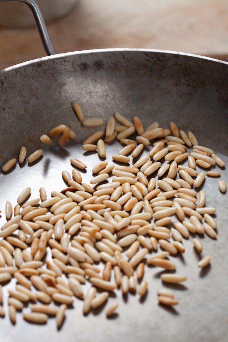 Pine nuts being roasted in a pan