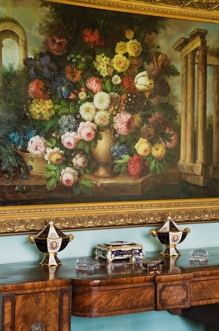 Floral painting with gilt frame above antique wooden console table