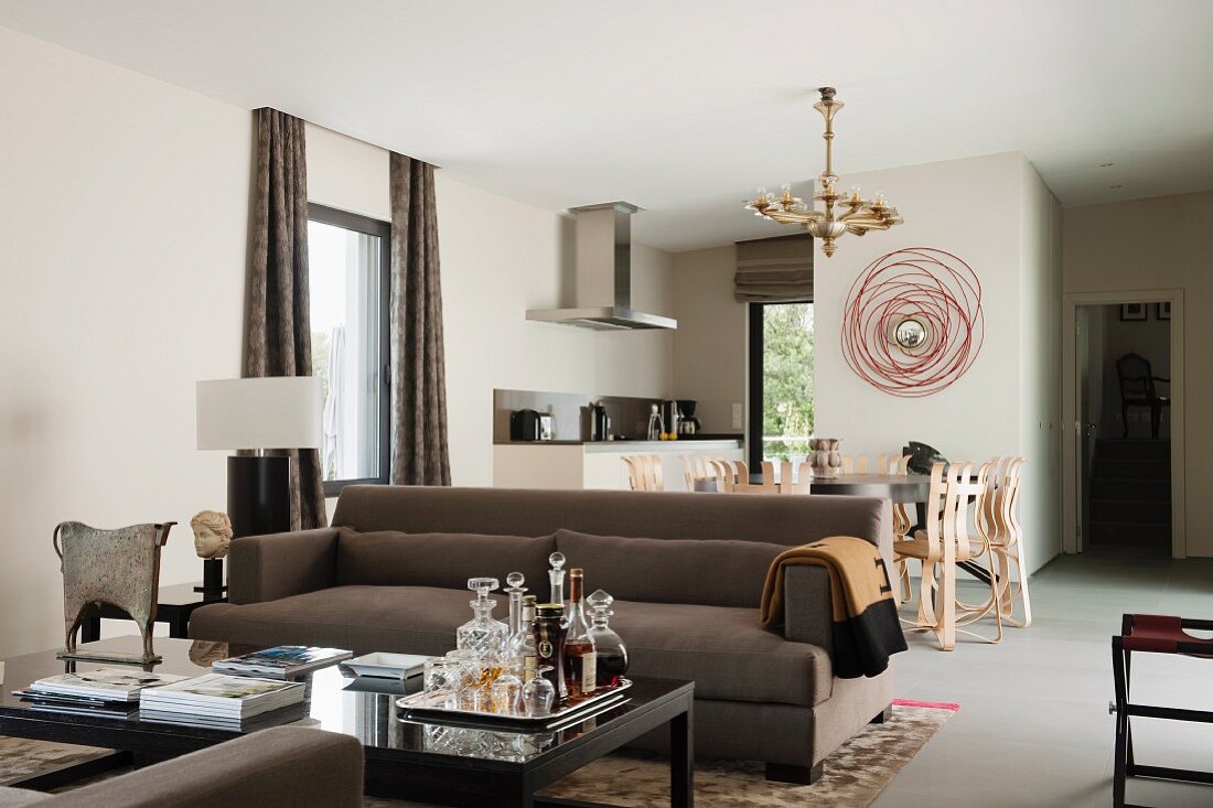 Drinks tray on coffee table and brown sofa in front of dining area in classic, modern, open-plan interior