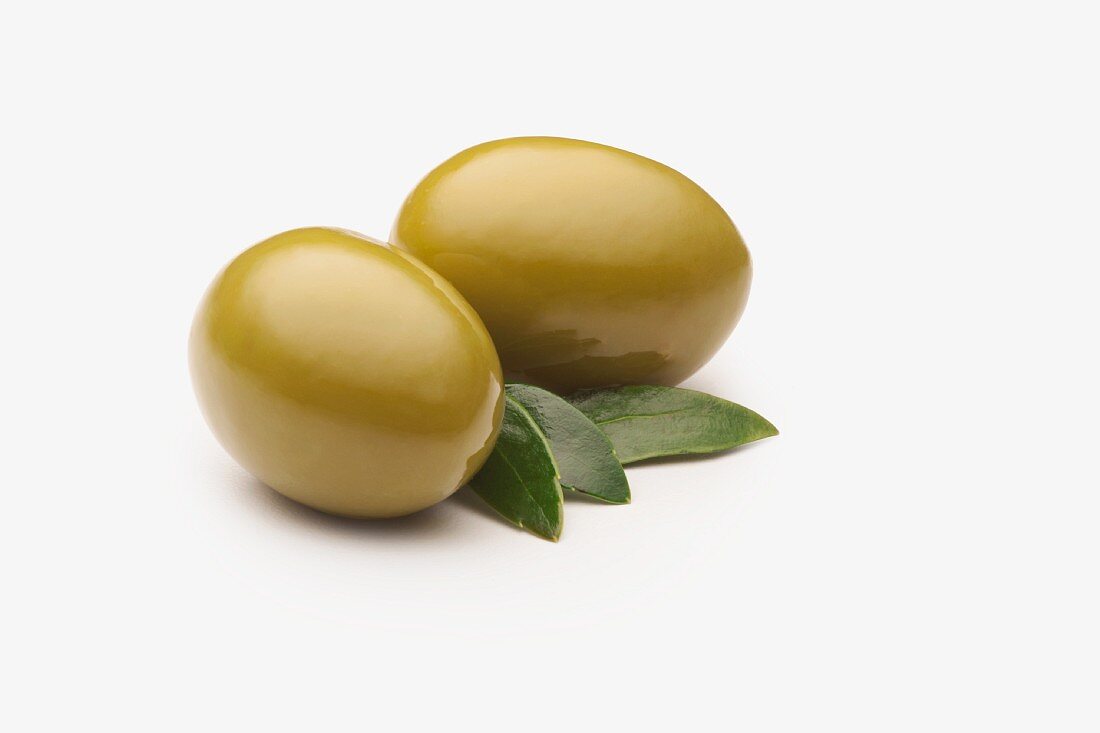 Zwei grüne spanische Oliven vor weißem Hintergrund