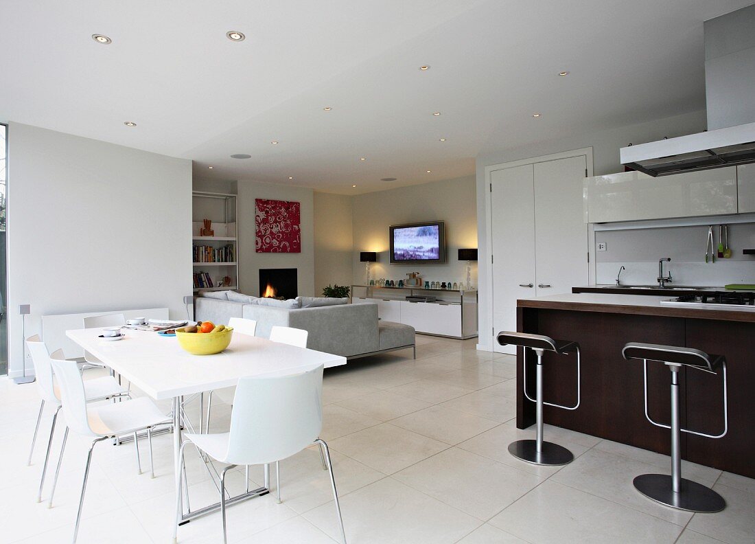 Modern dining table across from a counter with bar stools in an open living room