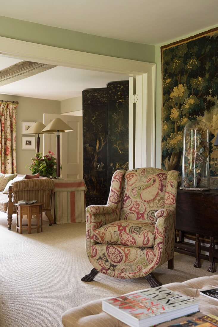 Polstersessel mit Paisley-Muster vor Wandbehang in traditionell englischem Wohnraum