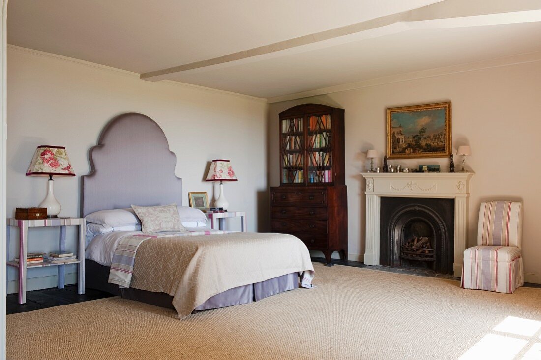 Doppelbett mit repräsentativem Kopfteil, englischer Bücherschrank und Kamin im wohnlichen Schlafzimmer