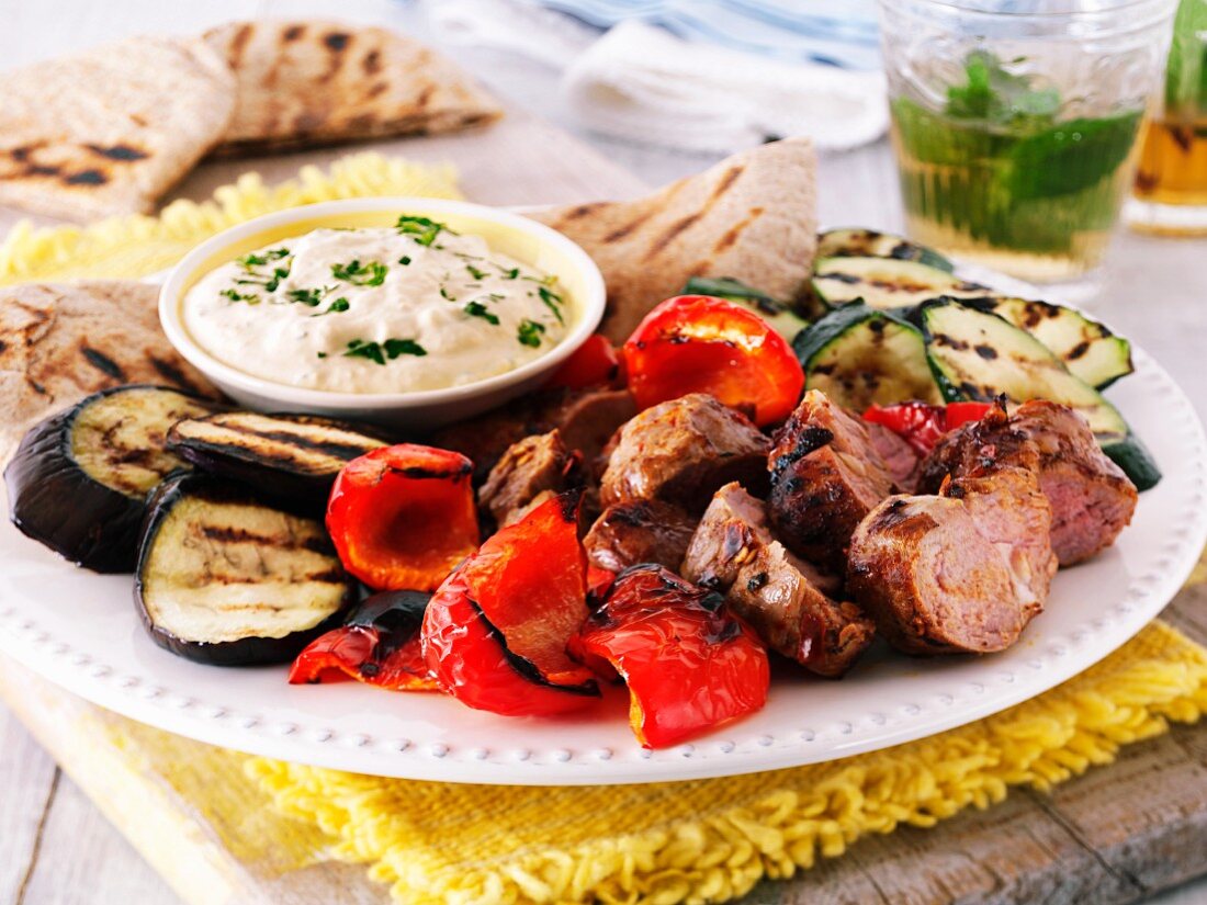 Grillteller mit Lammfleisch, Paprika, Auberginen, Zucchini und Hummus-Dip, dazu Pitabrot