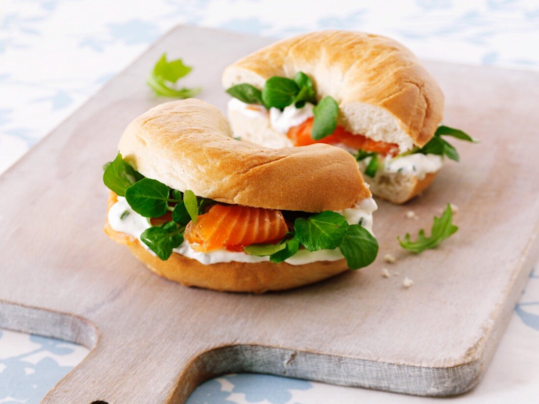 Cream cheese, bittercress and smoked salmon bagel on a chopping board