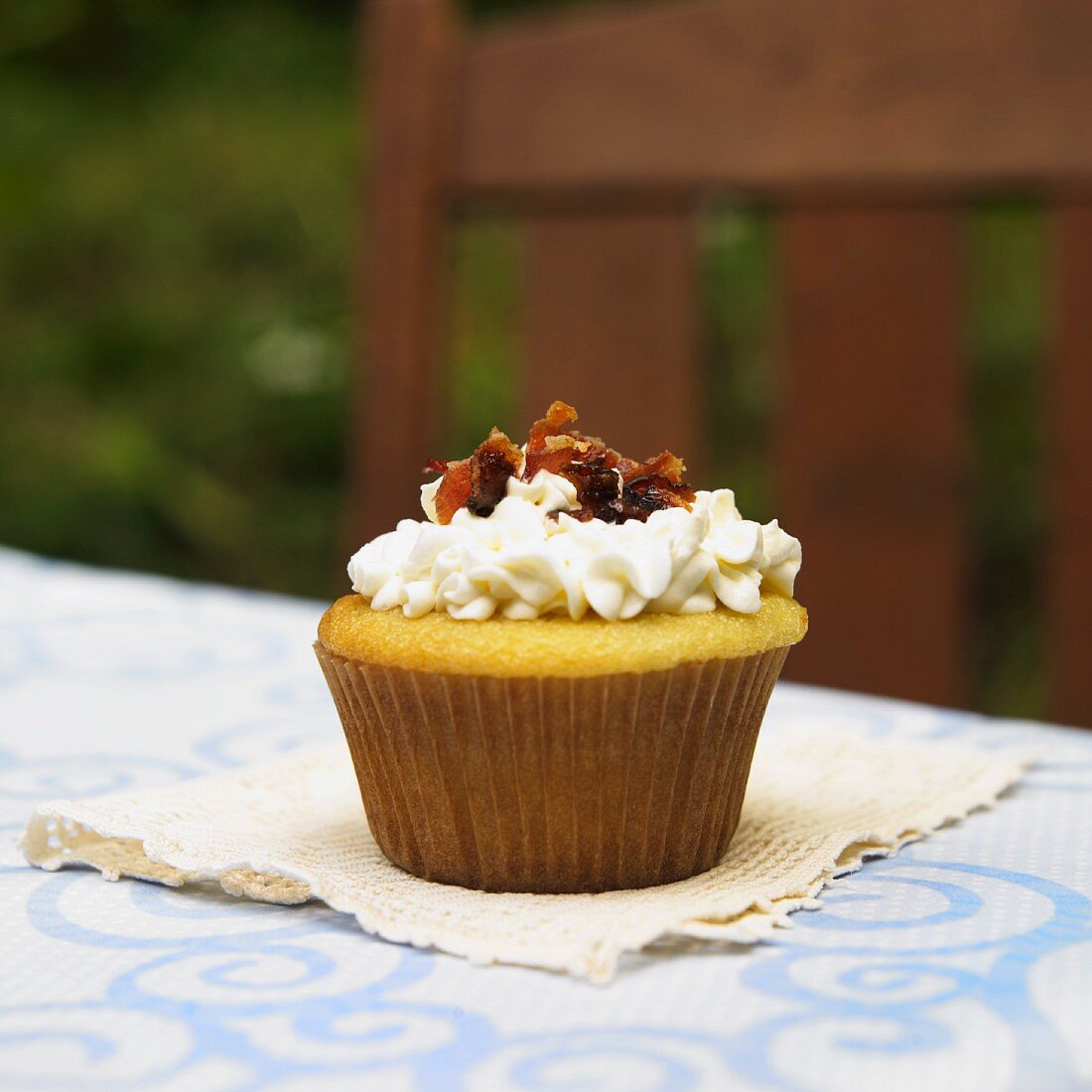 Ein Vanille-Cupcake mit Ahornsirupcreme & Speckwürfeln