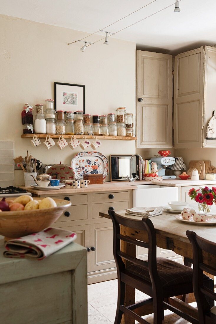 Dining area in front of kitchen counter below open spice shelf in English country-house kitchen