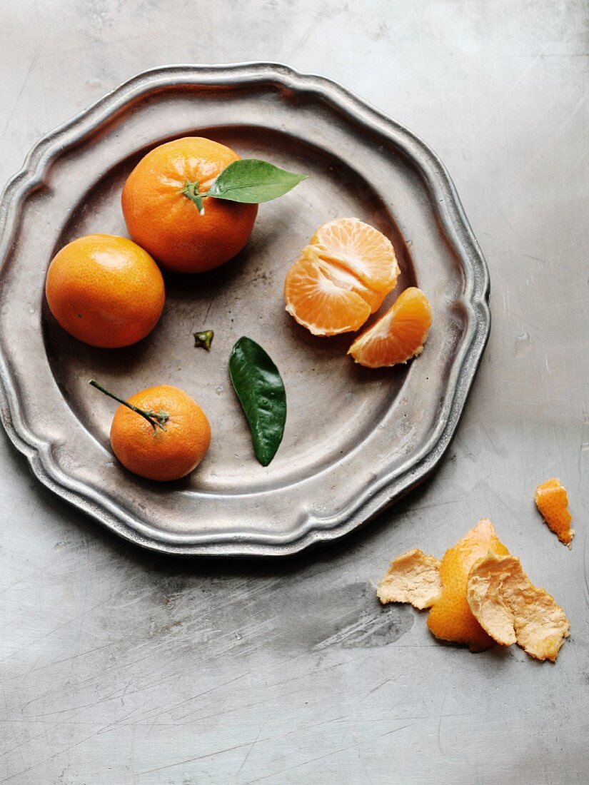 Clementinen ganz und geschält auf einer Platte
