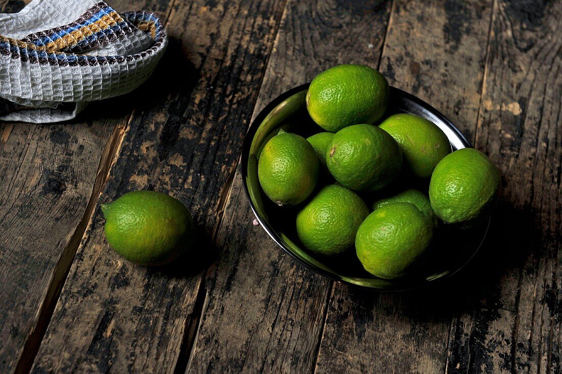 A bowl of limes on a wooden surface