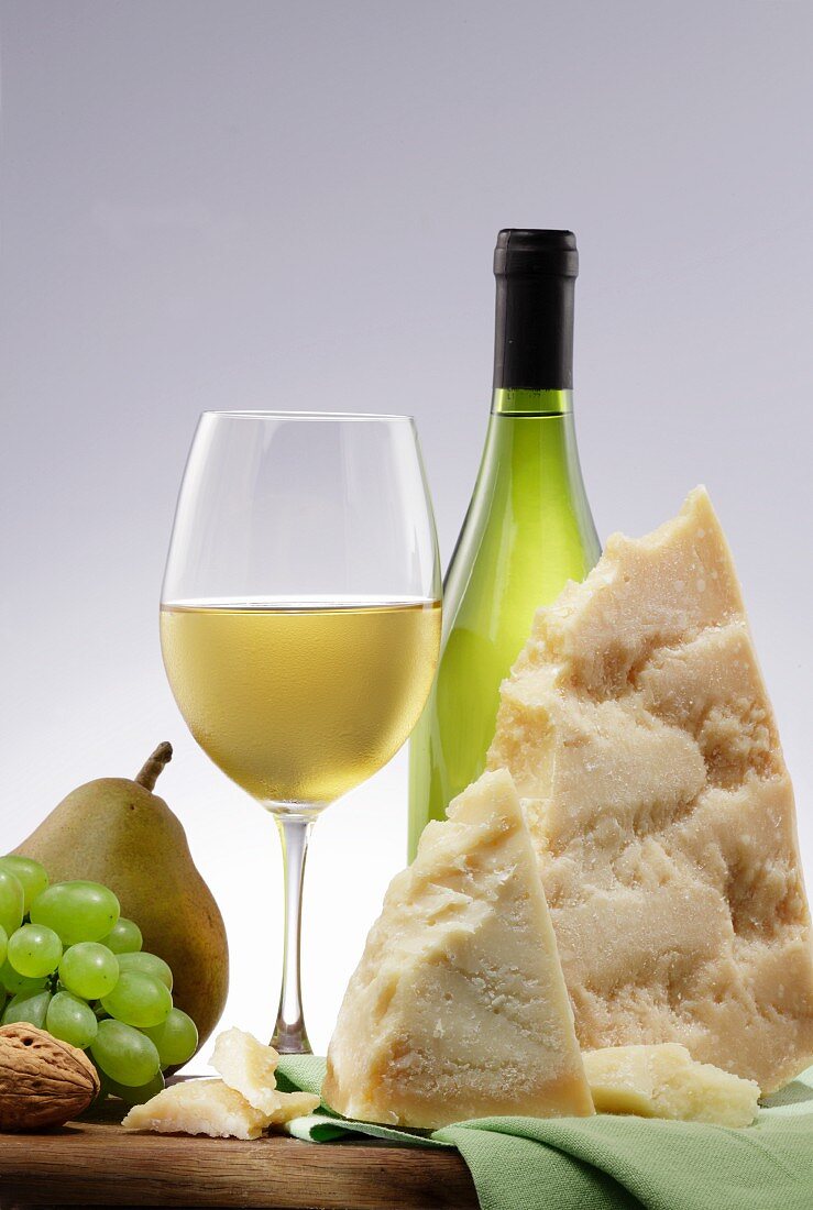 An arrangement of white wine, cheese, fruit and nuts
