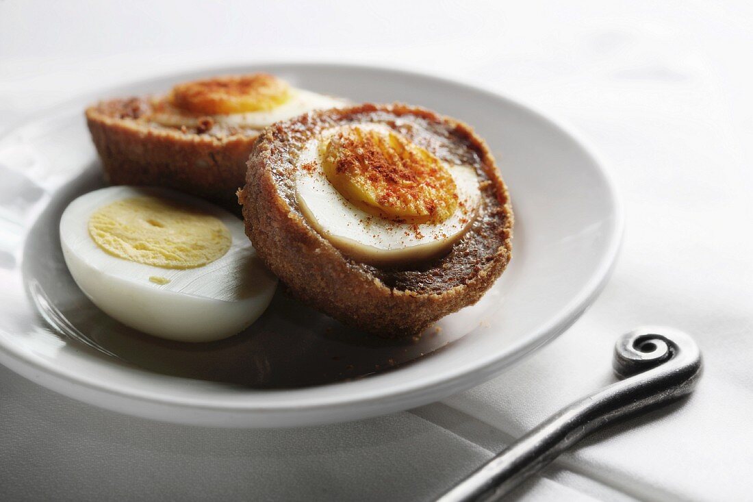 Scotch Eggs; Boiled Eggs Wrapped in Sausage Meat and Fried; Half of a Boiled Egg