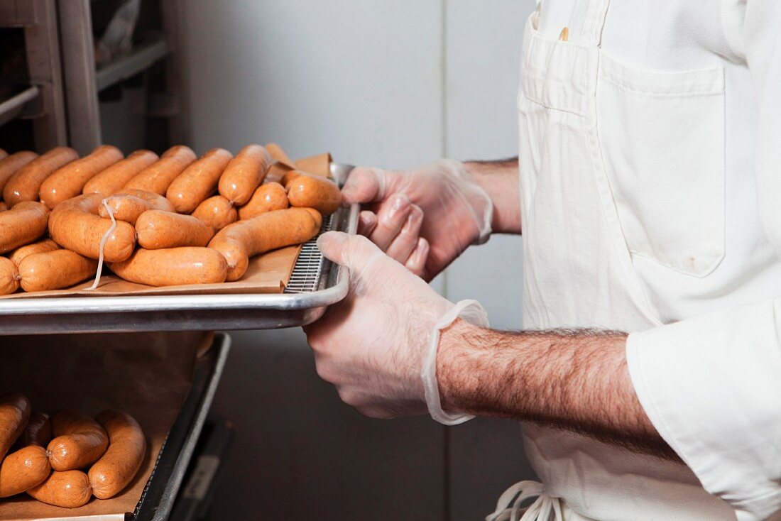 Butcher with tray of sausages