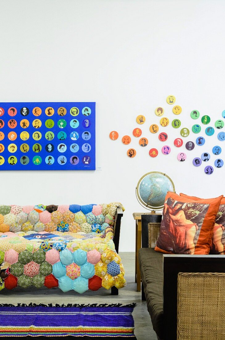 Sofa with patchwork blanket next to traditional bench and wall artistically decorated with portraits