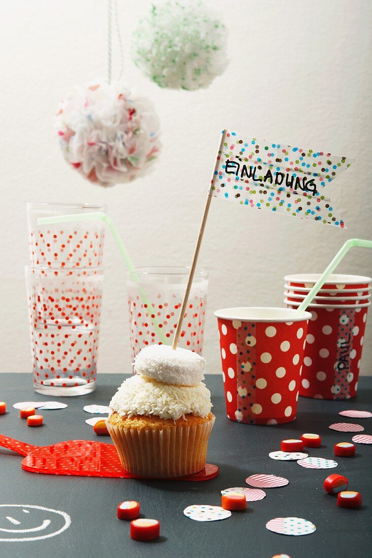 Cupcake with washi tape flag, paper cups, glasses and party decorations