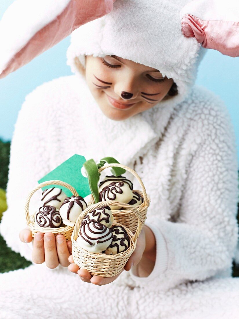 A girl, dressed as the Easter bunny, holding little baskets of chocolate eggs