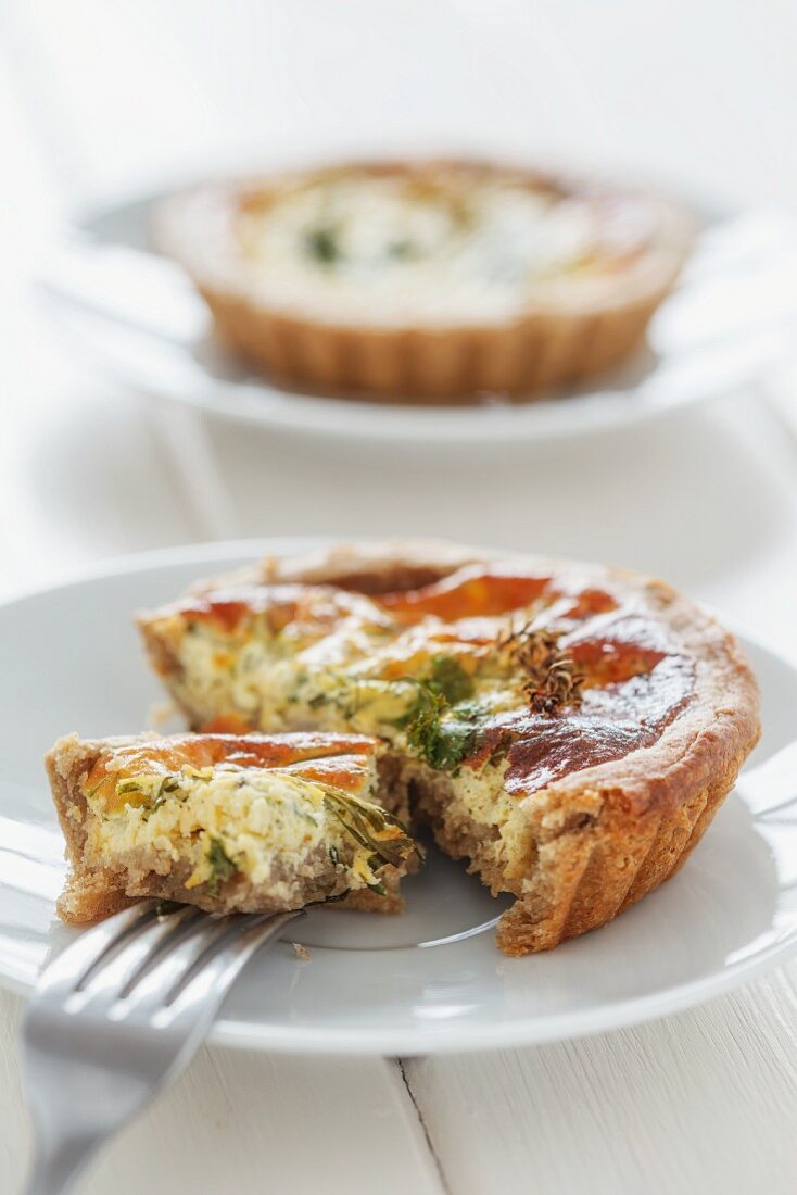 A mini quiche with herbs with a bite taken out