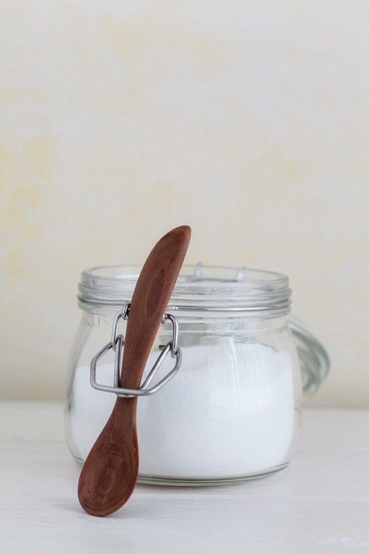 A jar of sugar with a wooden spoon