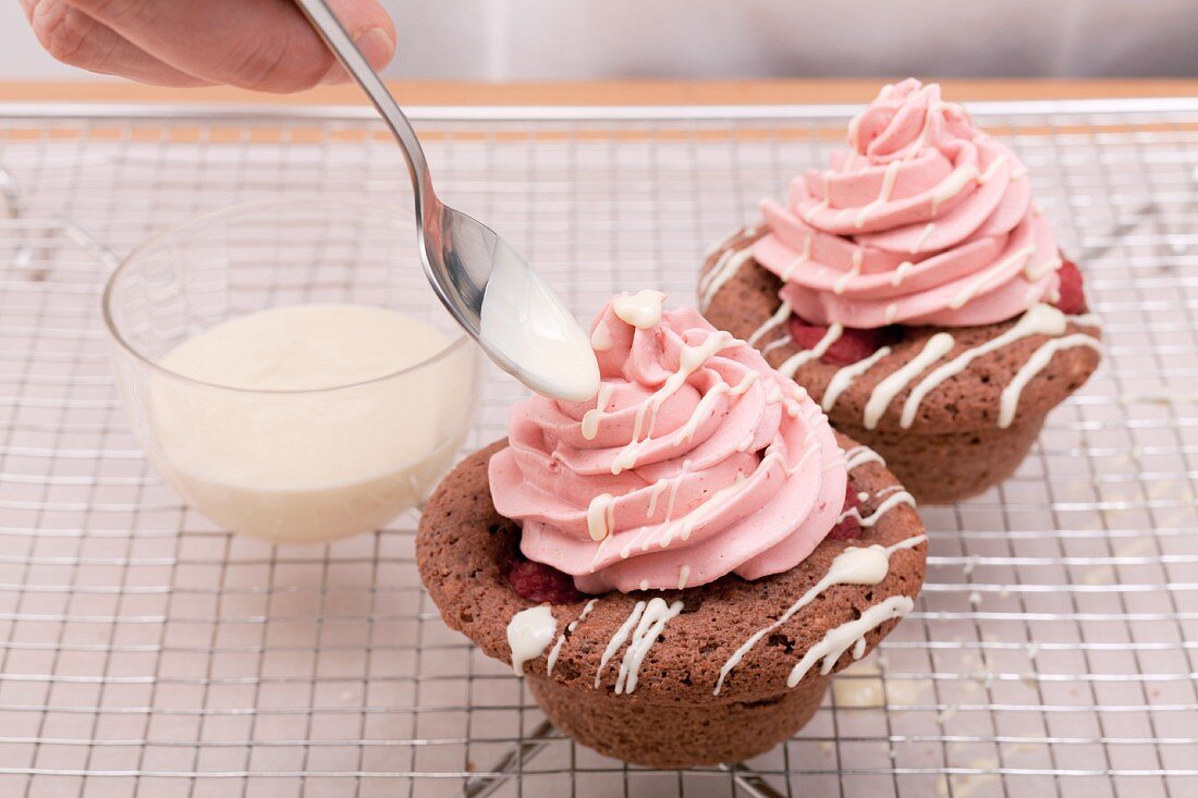 Two raspberry cupcakes on a cooling rack