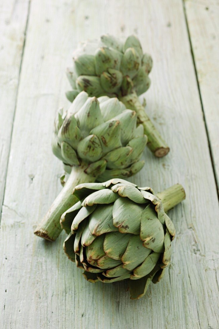 Three artichokes on a wooden surface
