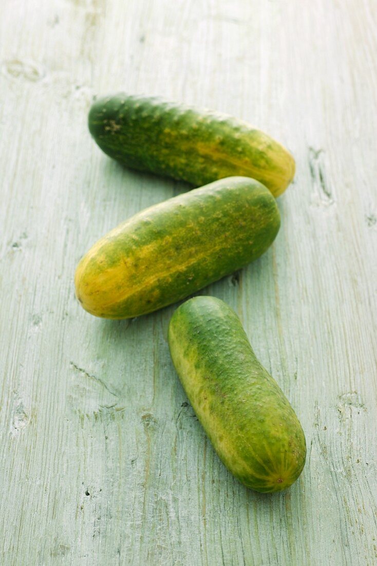 Three gherkins on a wooden surface