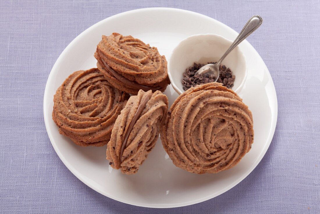 Piped biscuits with chocolate filling on a white plate