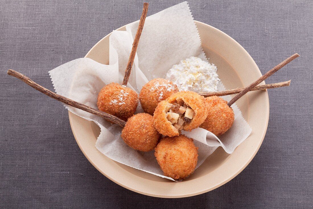 Frittierte Teigbällchen mit süßer Füllung in einer beigen Schale