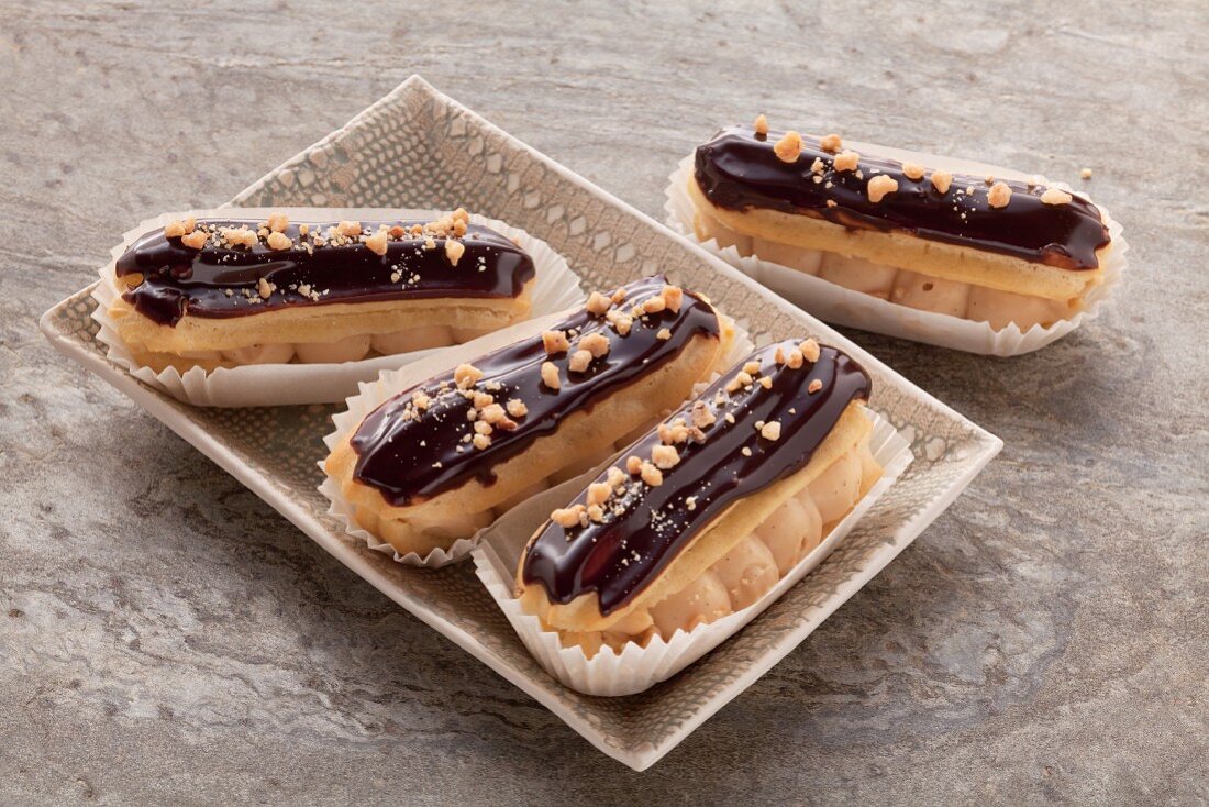 Eclairs with a chocolate glaze in a small oblong dish on a grey surface