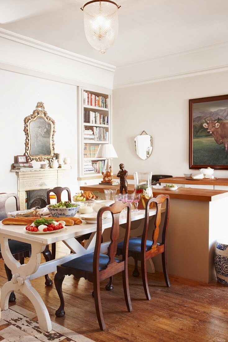 Set dining table and antique chairs in front of open fireplace