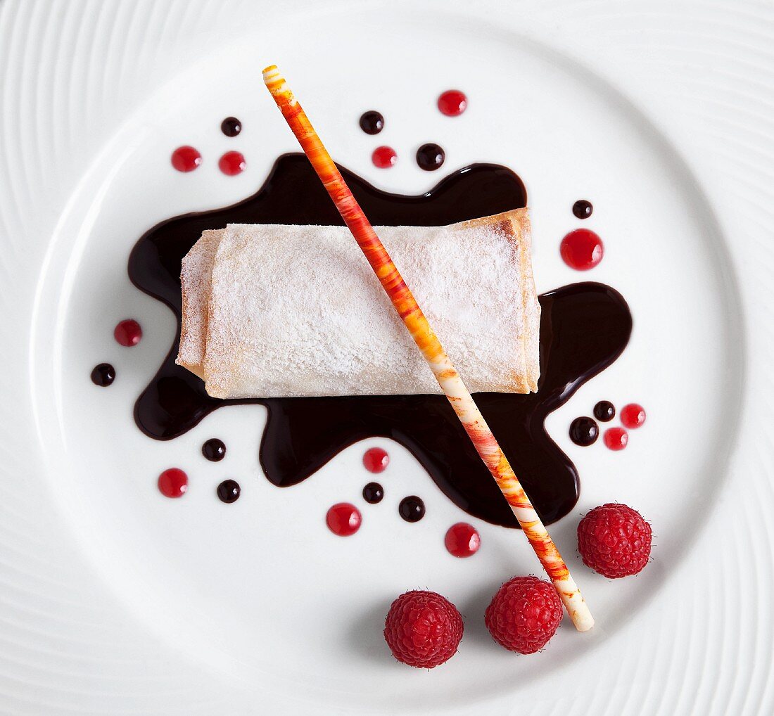 Rolled Dessert Crepe with Chocolate and Raspberry Sauce, Fresh Raspberries and a Sugar Stick